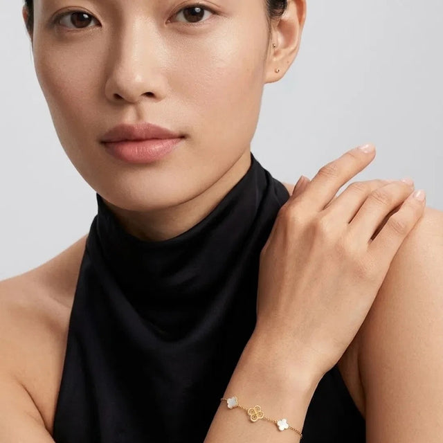 Woman with her hand on her shoulder wearing the Clover Shell Pearl Bracelet in 14K gold-plated 925 silver