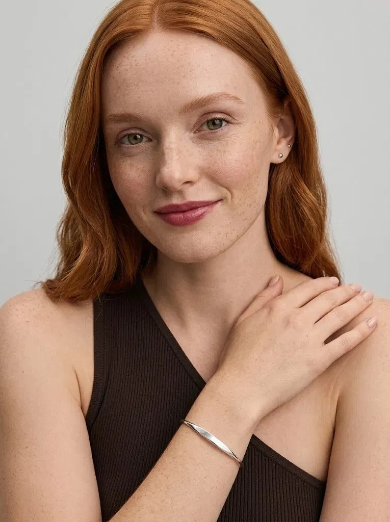 Smiling woman with her hand on her shoulder wearing the Personalized Letter Bangle in 925 sterling silver