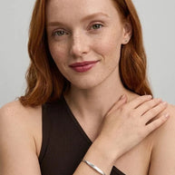Smiling woman with her hand on her shoulder wearing the Personalized Letter Bangle in 925 sterling silver