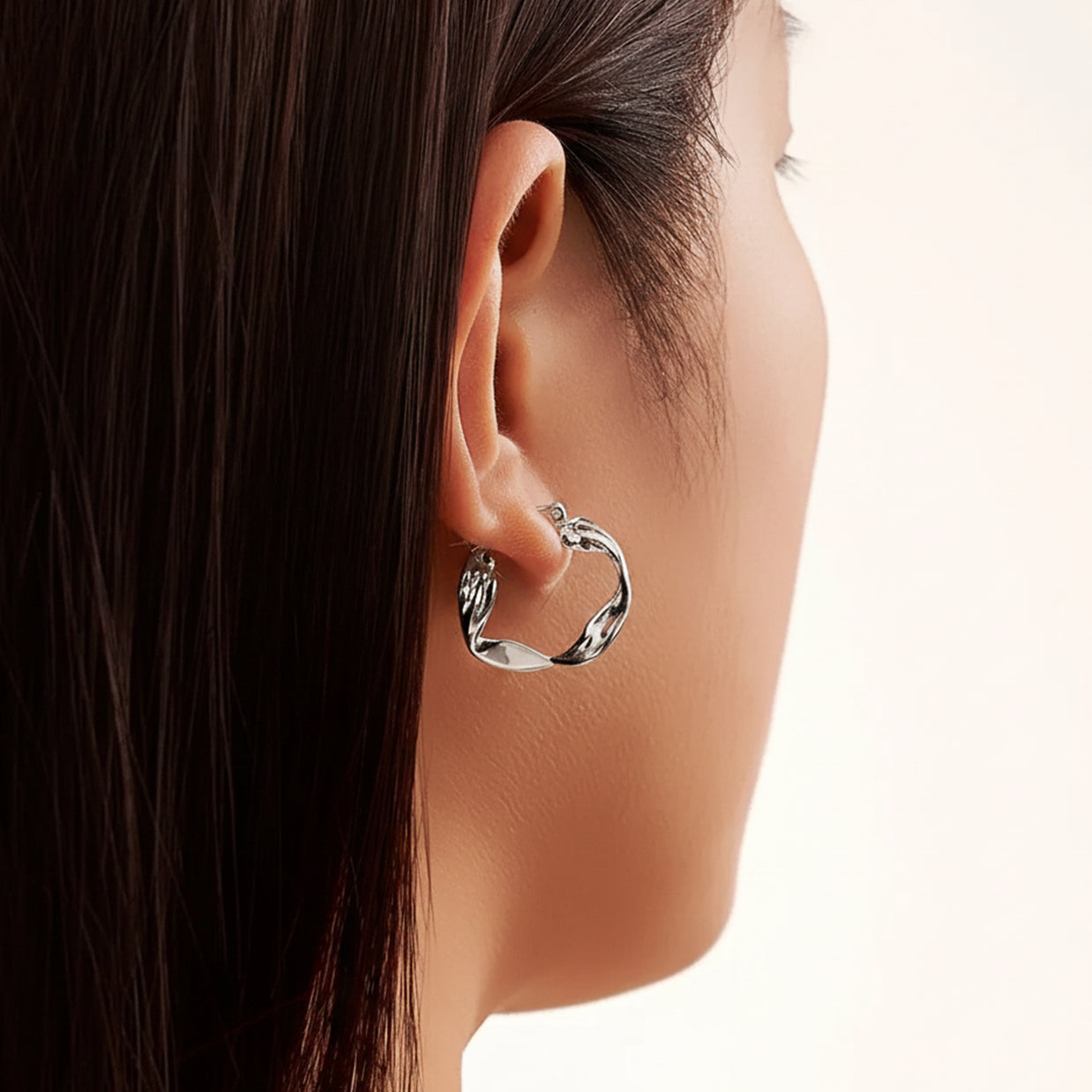 Close-up of a rhodium-plated silver wavy hoop earring highlighting its fluid design.