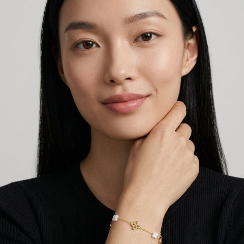 Woman with black hair wearing the 14K gold-plated Clover Shell Pearl Bracelet with white shell clovers and filigree gold clovers