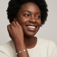 Smiling woman wearing the 925 silver Clover Shell Pearl Bracelet with white shell clovers and filigree silver clovers