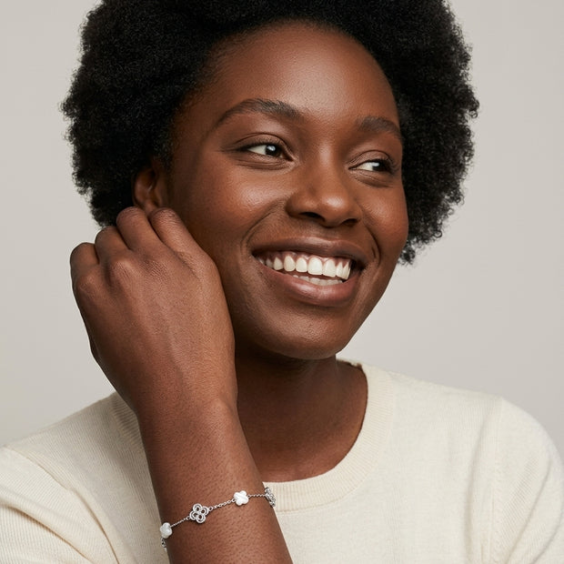 Smiling woman wearing the 925 silver Clover Shell Pearl Bracelet with white shell clovers and filigree silver clovers