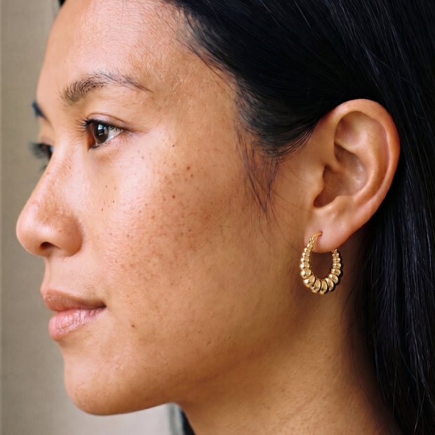 Loretana Thick Twisted Hoops in 14K gold-plated 925 silver worn on the ear, chunky graduated ribs