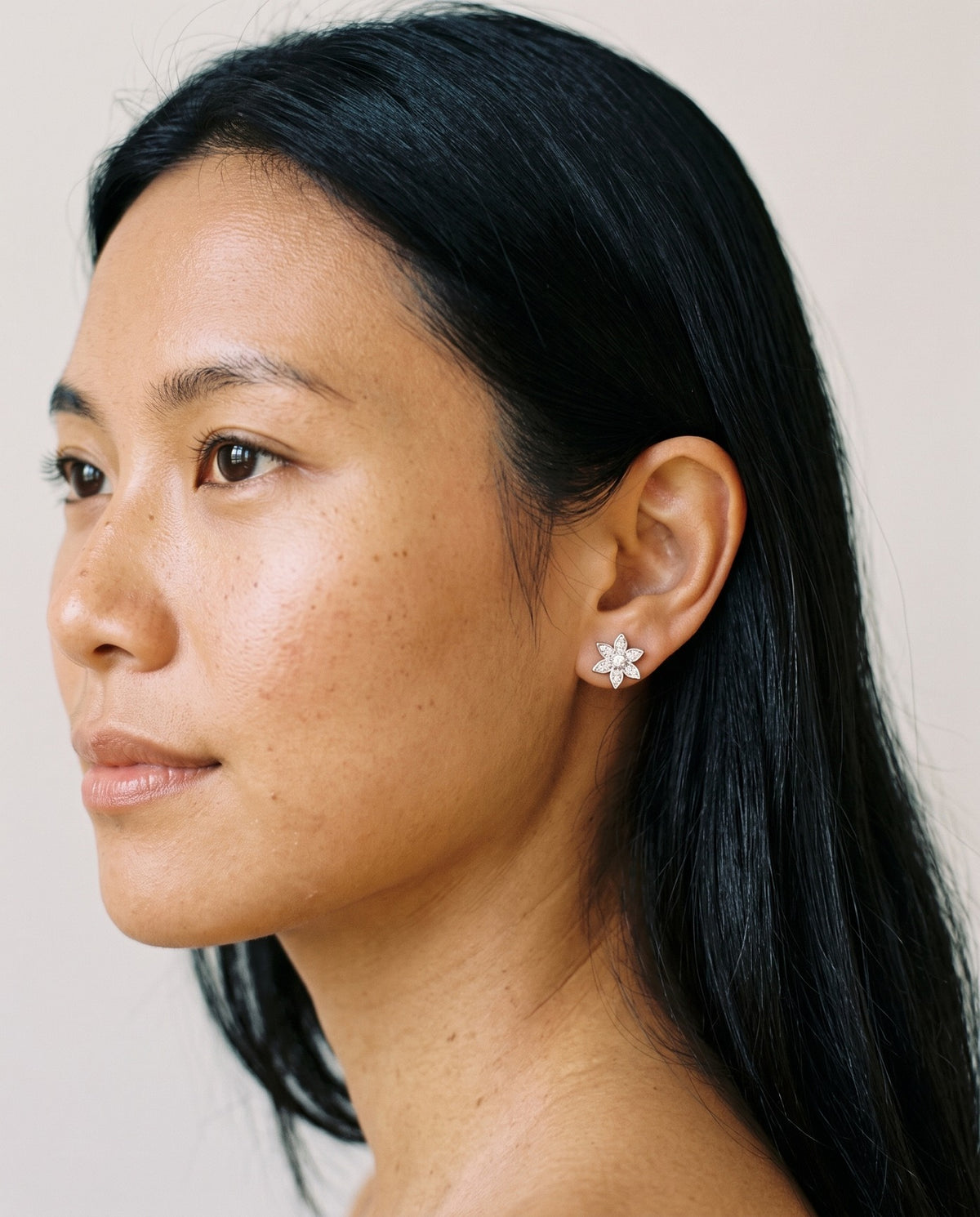 Loretana 925 silver flower stud earring with six petals and clear CZ stones, worn on the ear