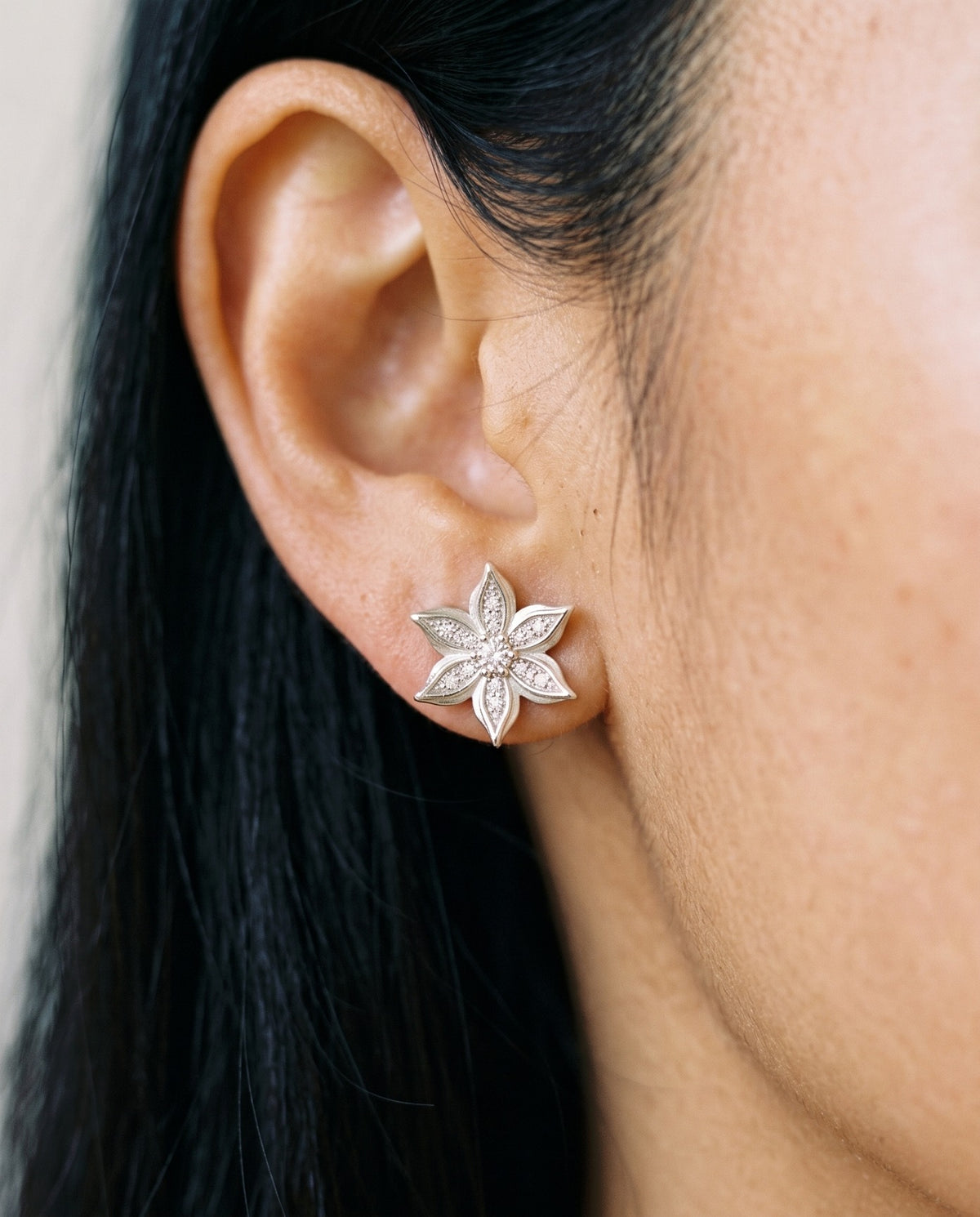 Close-up of Loretana 925 silver flower stud earring with CZ stones on the earlobe
