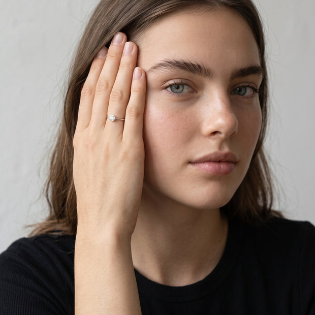 Loretana R43-S silver bezel solitaire ring worn by model, hand at temple