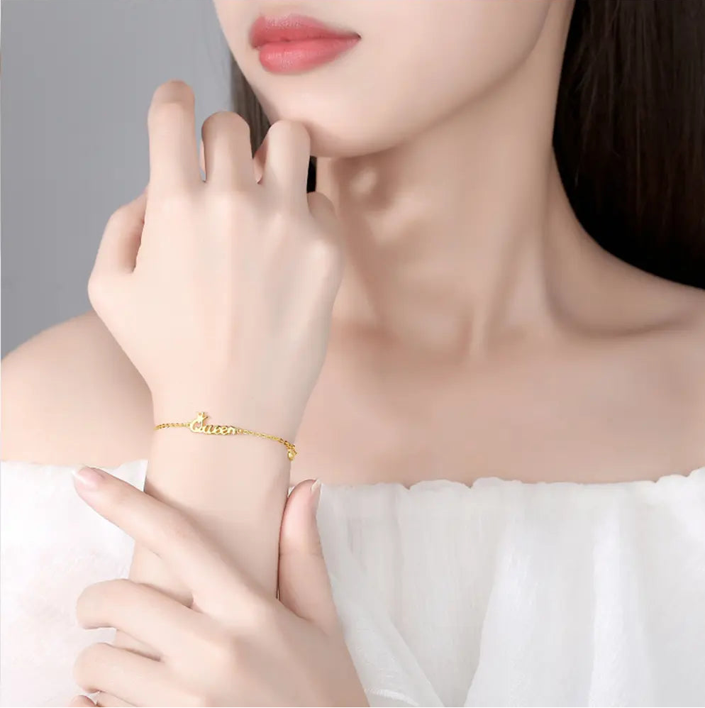 Close up of 14K gold bracelet showing custom initial and minimalist crown pendant