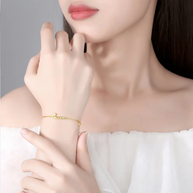 Close up of 14K gold bracelet showing custom initial and minimalist crown pendant