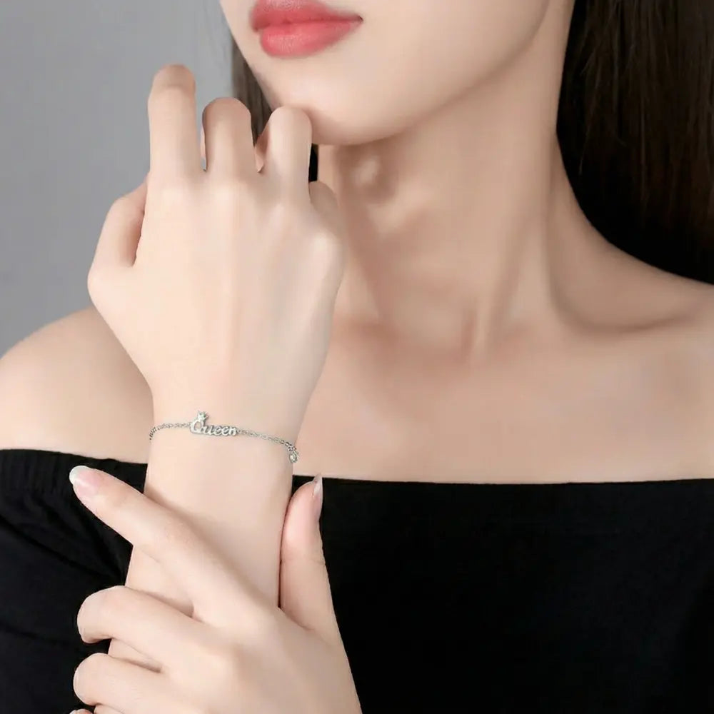 Close up of 925 silver bracelet showing custom initial and minimalist crown pendant