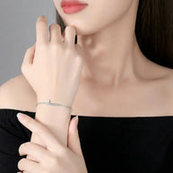 Close up of 925 silver bracelet showing custom initial and minimalist crown pendant