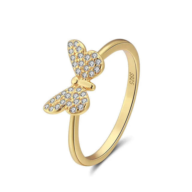 Hand model wearing the gold butterfly filigree ring in 925 sterling silver with 14K gold plating, openwork wings catching warm light against the finger. Hallmarked Loretana piece, hand-finished in Kaunas.