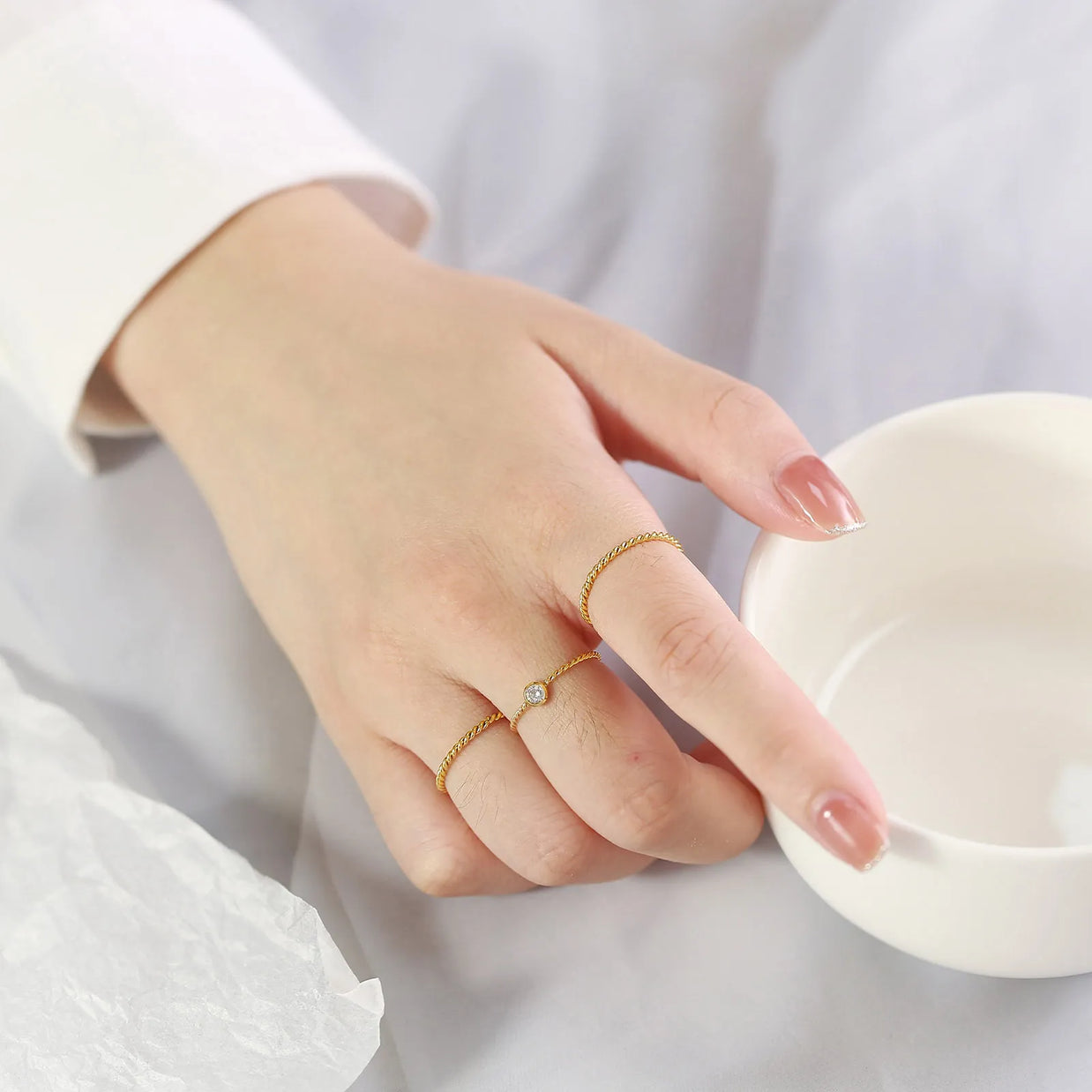 Close-up of a woman's hand wearing the 14K gold-plated twisted rope band for a stackable look.