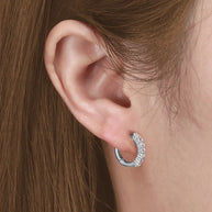 Silver round CZ hoop worn alone on the earlobe, rhodium-plated 925 silver.