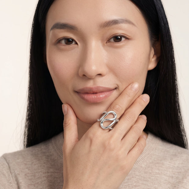 Model with fingertips at her cheek wearing the chunky 925 silver geometric figure-8 open ring.