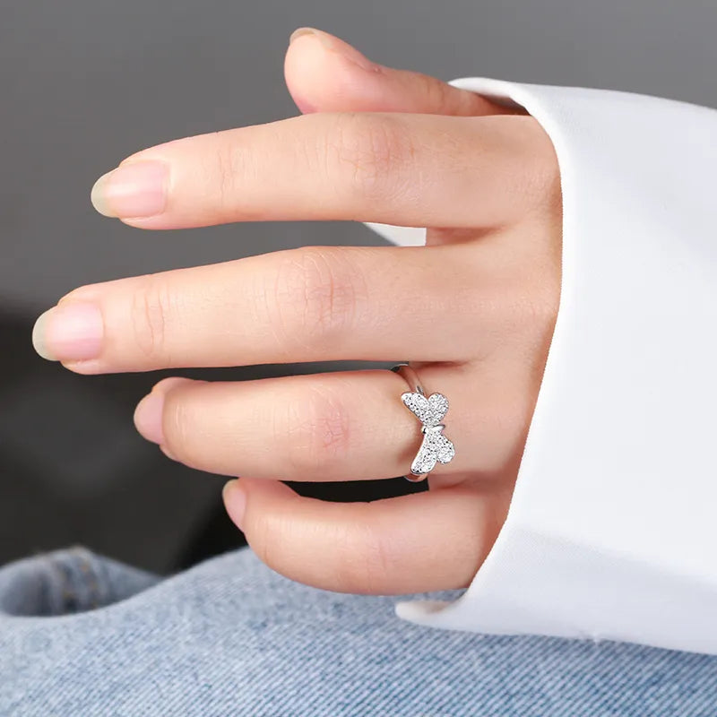 Hand model wearing the silver butterfly filigree ring in 925 sterling silver with rhodium plating, openwork wings catching daylight against the finger. Hallmarked Loretana piece, hand-finished in Kaunas.