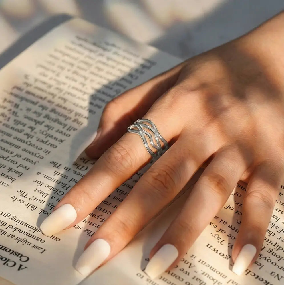 Rhodium-plated 925 silver twisted wave adjustable ring featuring a polished sculptural design on white.