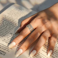 Rhodium-plated 925 silver twisted wave adjustable ring featuring a polished sculptural design on white.